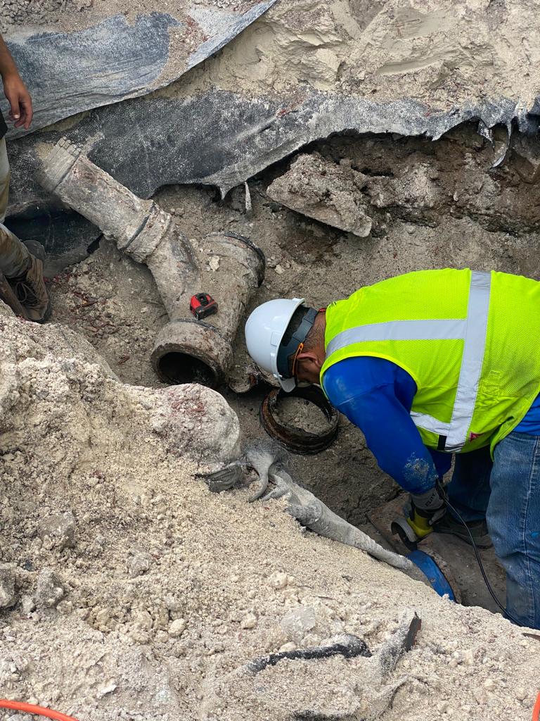 Recommended ALT Text: Utility worker inspecting an underground pipe during excavation in Miami-Dade County