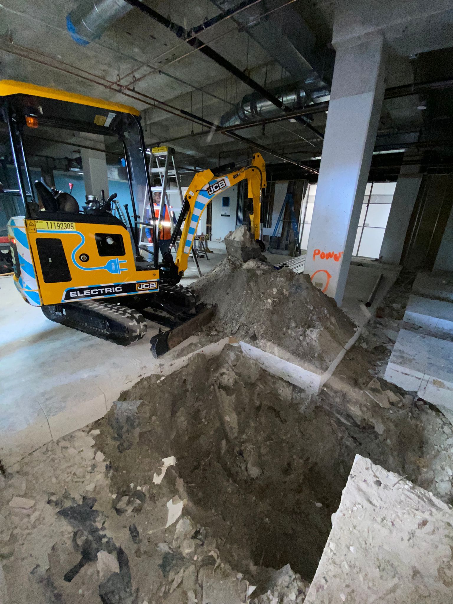 Construction crew using excavation equipment for underground utility work inside a building