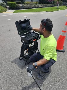 Technician performing sewer camera inspection using specialized underground utility inspection equipment